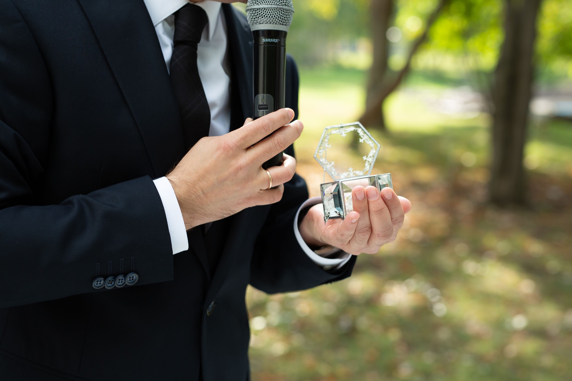 A showman in a classic suit with a microphone at a wedding exit ceremony